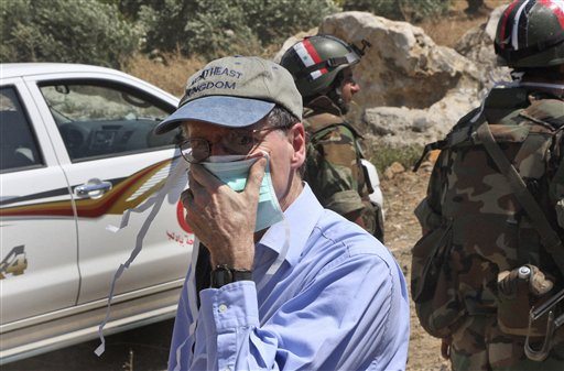 FILE - In this June 20, 2011 photo taken during a government-organized tour for foreign diplomats and the media, US ambassador in Syria Robert Ford, covers his nose during his visit with other foreign diplomats to a mass grave, in Jisr el-Shughour, north of Syria. State Department spokesman Mark Toner said Monday, Oct.