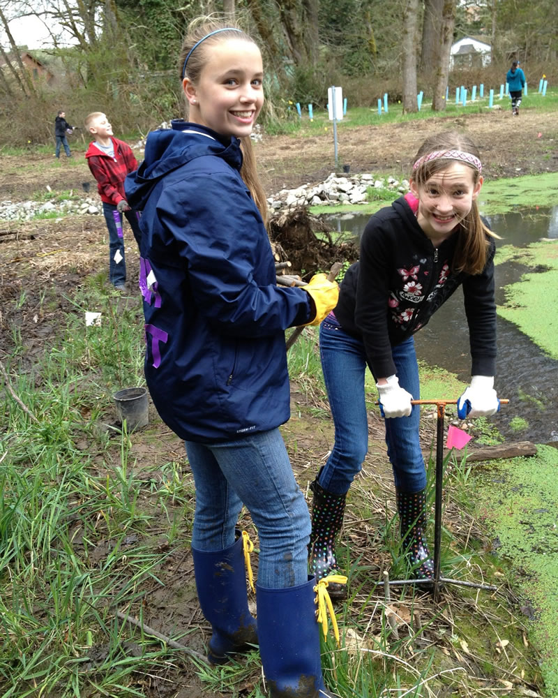 Pleasant Valley: Rylie Krout, left, and Heidi Nordahl, sixth-graders at Pleasant Valley Middle School, plant native plants to restore fish habitat at Pleasant Valley Community Park in March.