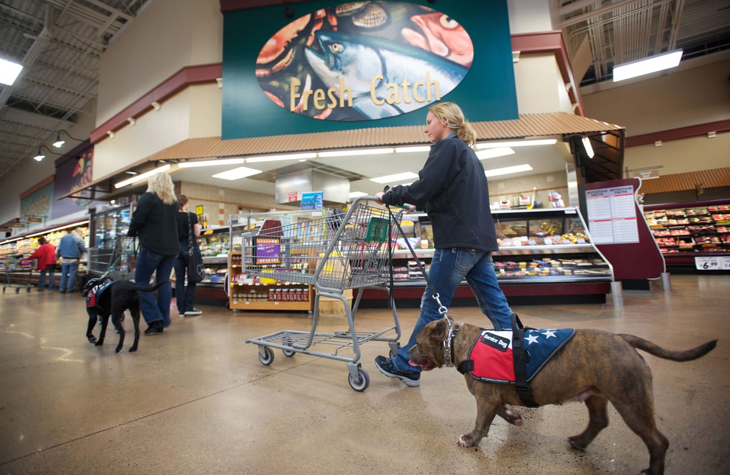 Shannon Walker, left, and Ora Evans, right, walk Oso and Diamond, respectively, through the Battle Ground Fred Meyer on Wednesday as part of their therapy dog training.
