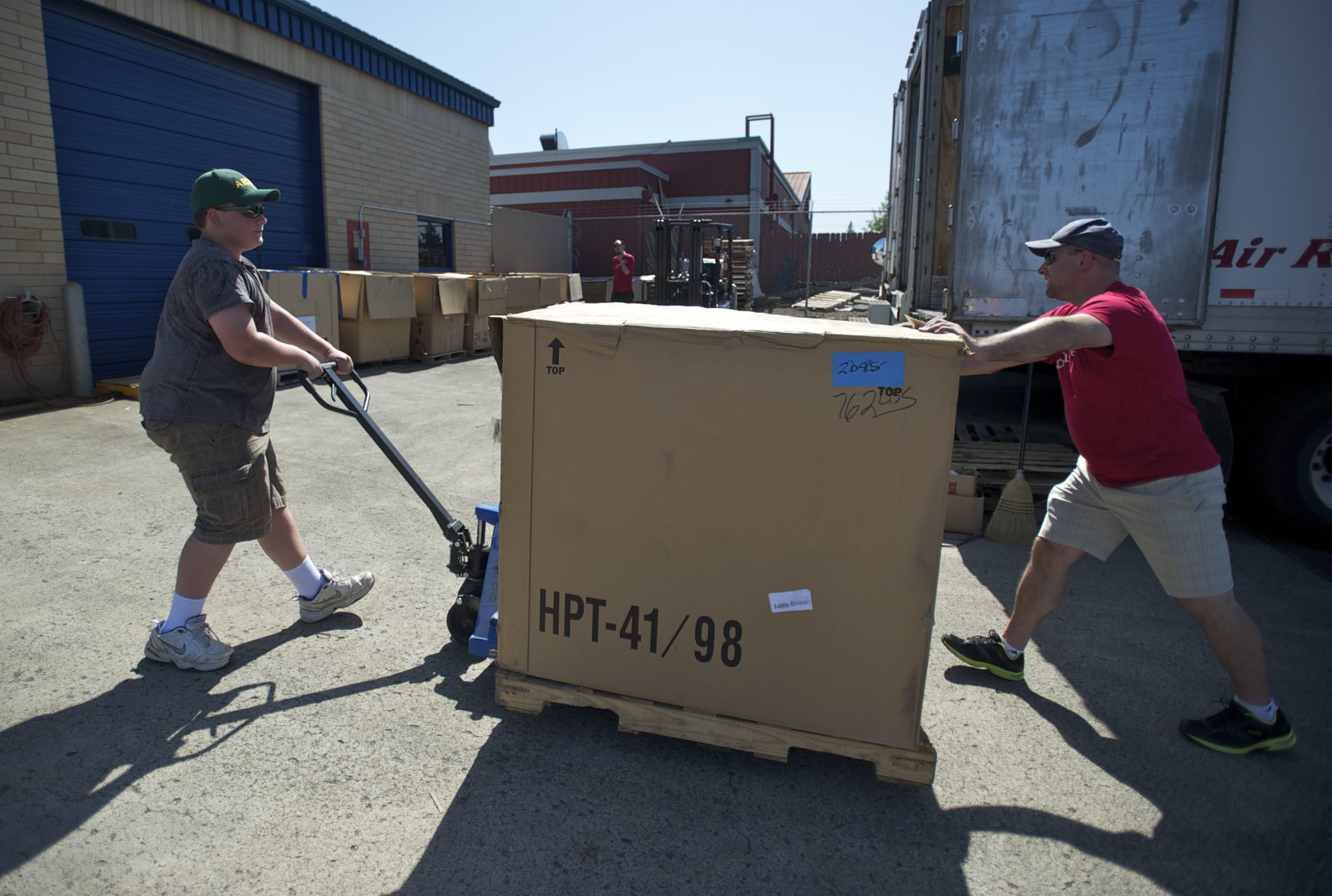 Brandon Hanson, 13, left, and his father, Kyle, move a large box filled with canned goods at the Caples Road post office.