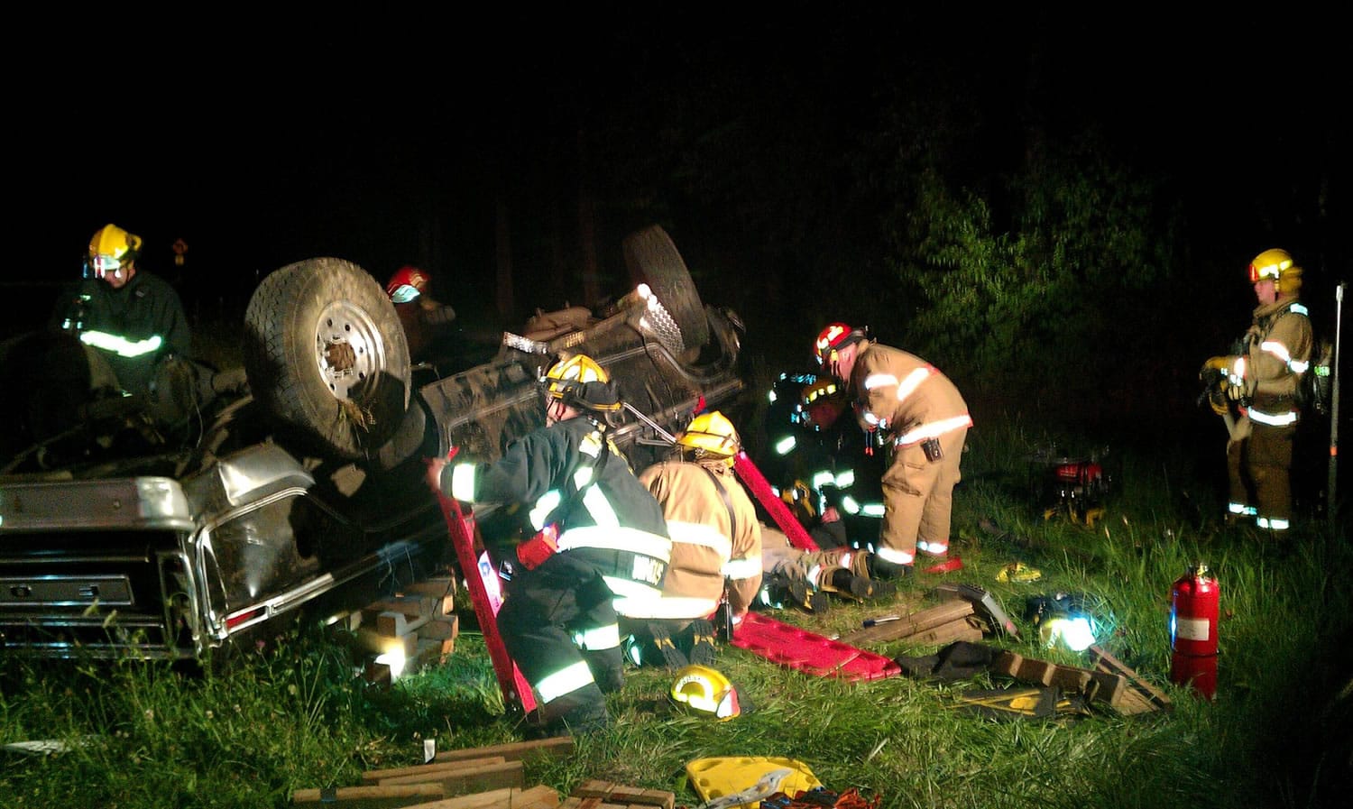 Firefighters stabilize a 1977 Ford pickup just off Northwest Lower River Road on Friday night before freeing two trapped people.