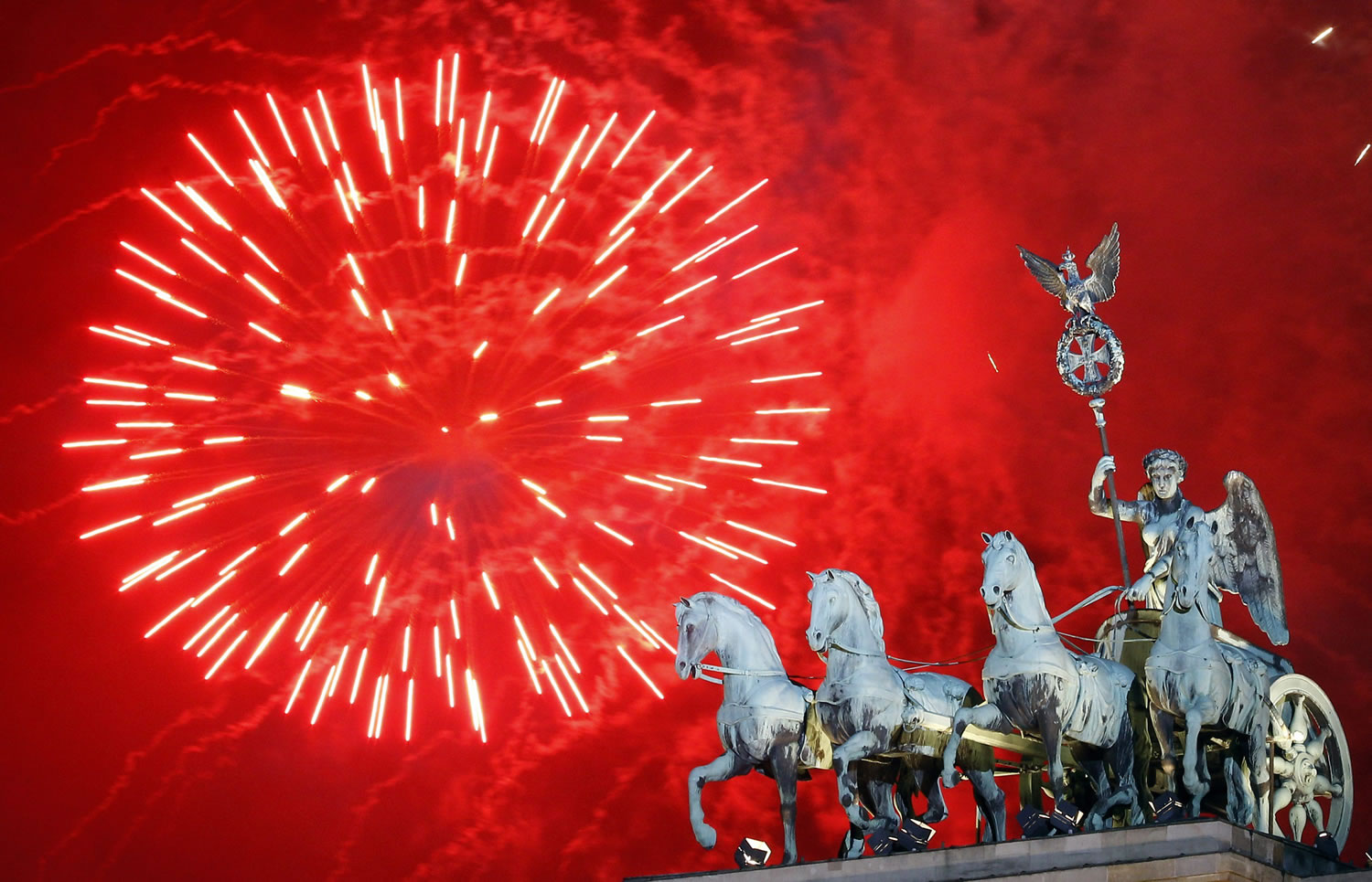 Fireworks light the sky Sunday above the Quadriga at the Brandenburg Gate in Berlin shortly after midnight, greeting the New Year, Sunday.