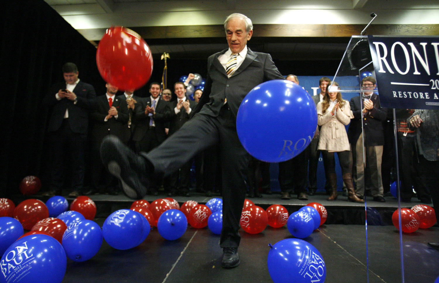 Republican presidential candidate Rep. Ron Paul, R-Texas, kicks balloons from the stage after speaking to supporters following his loss in the Maine caucus to Mitt Romney Feb.