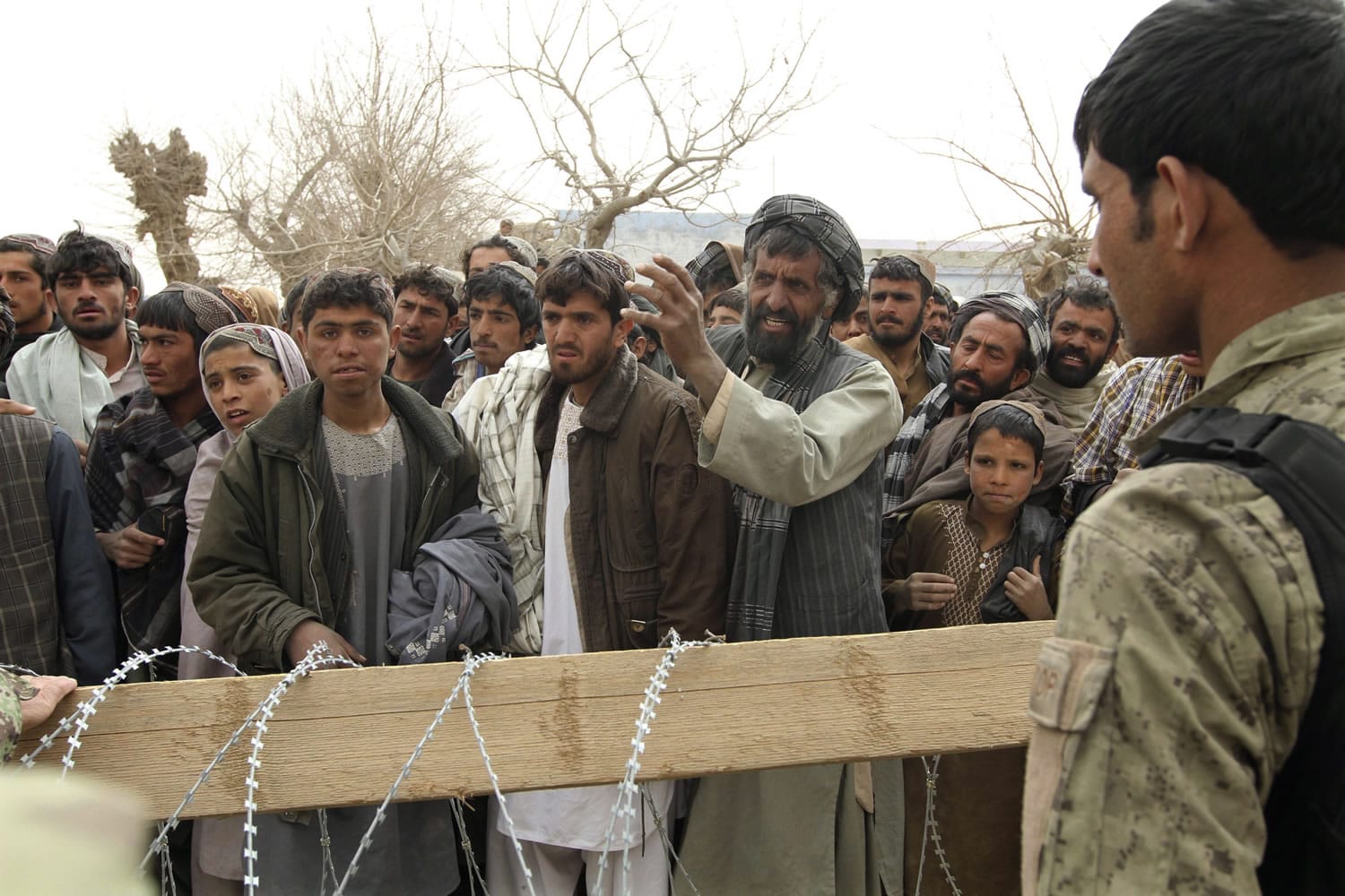 An Afghan soldier speaks to civilians gathered outside a military base in Panjwai, Kandahar province, south of Kabul, Afghanistan, on Sunday. A U.S. Army staff sergeant is accused of killing 16 Afghan civilians, most of them children, and then burning many of the bodies.
