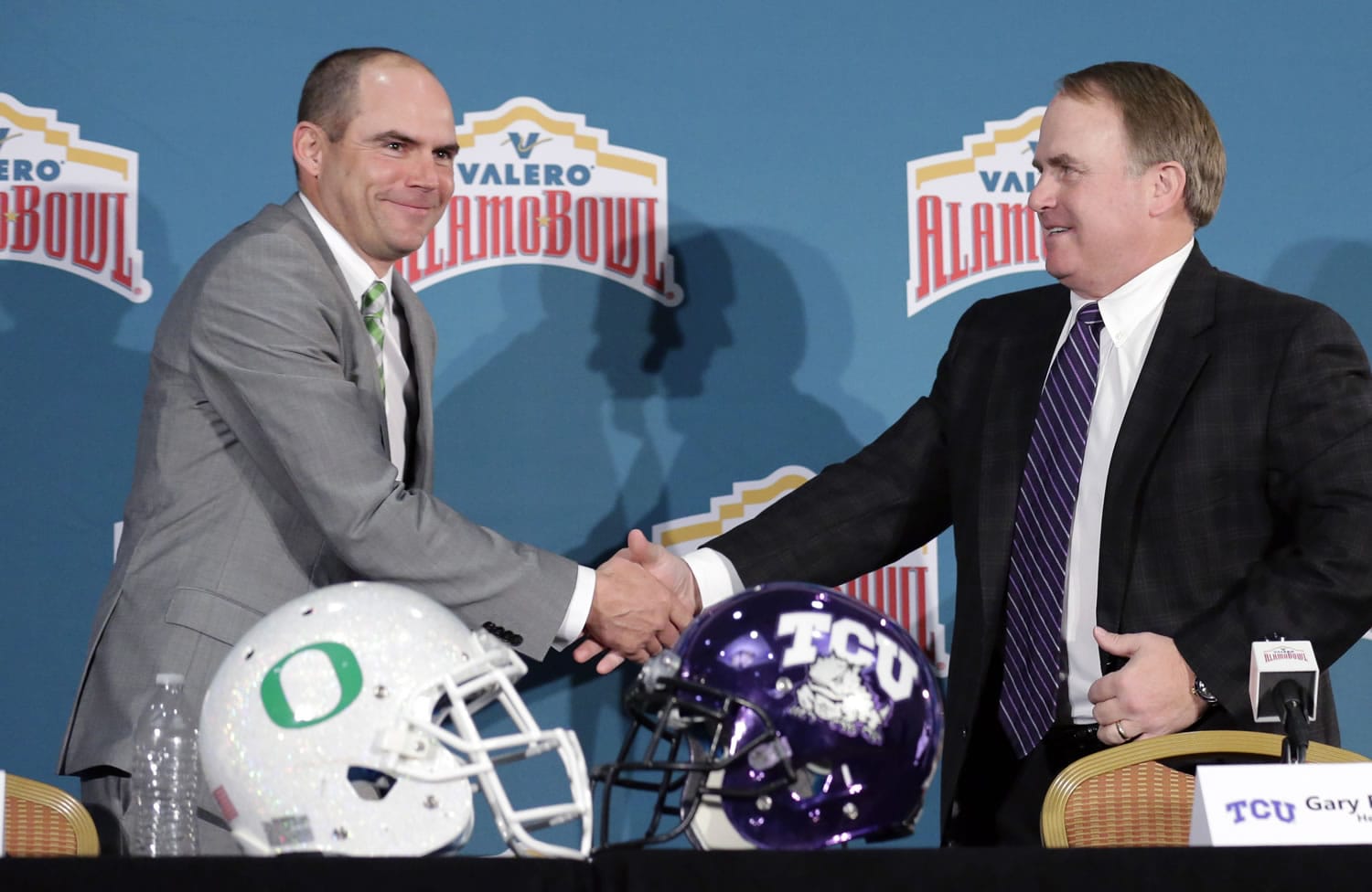Oregon head coach Mark Helfrich, left, and TCU head coach Gary Patterson, right, shake hands following a news conference for the Alamo Bowl NCAA college football game, Friday, Jan. 1, 2016, in San Antonio. The two teams meet on Saturday.