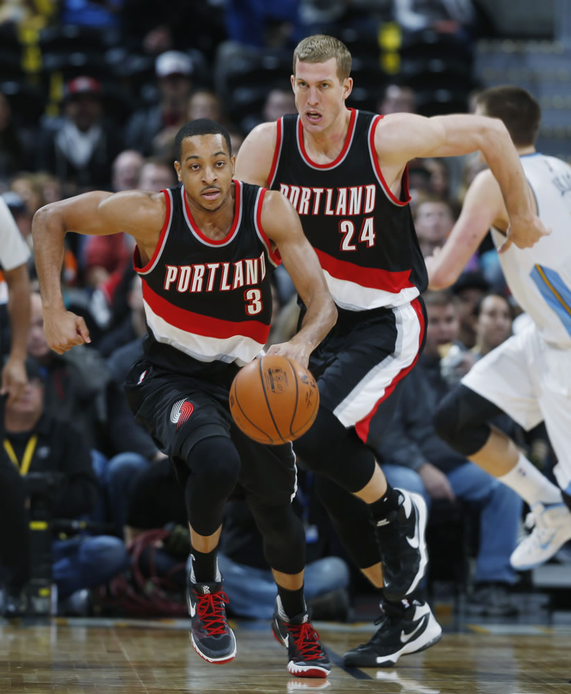 Portland Trail Blazers guard C.J. McCollum, front, picks up a loose ball as center Mason Plumlee follows down the court against the Denver Nuggets in the first half of an NBA basketball game, Sunday, Jan. 3, 2016, in Denver.