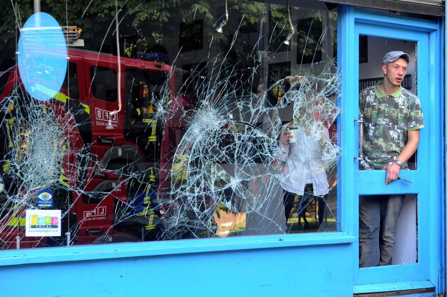 Shop keepers begin to clean up Tuesday on Ealing High Street in west London following a third straight day of riots.