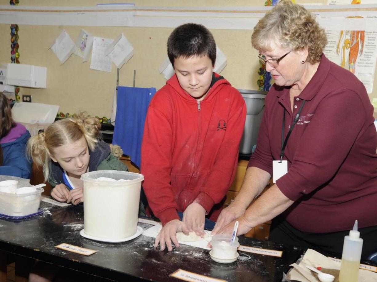 Hazel Wallin, left, watches as Sandy Brown, right, from Washington State University Extension, assists Calvin Ecaruan with his bread dough at Wy'east Middle School in Vancouver, WA, Monday, Nov 21, 2011.