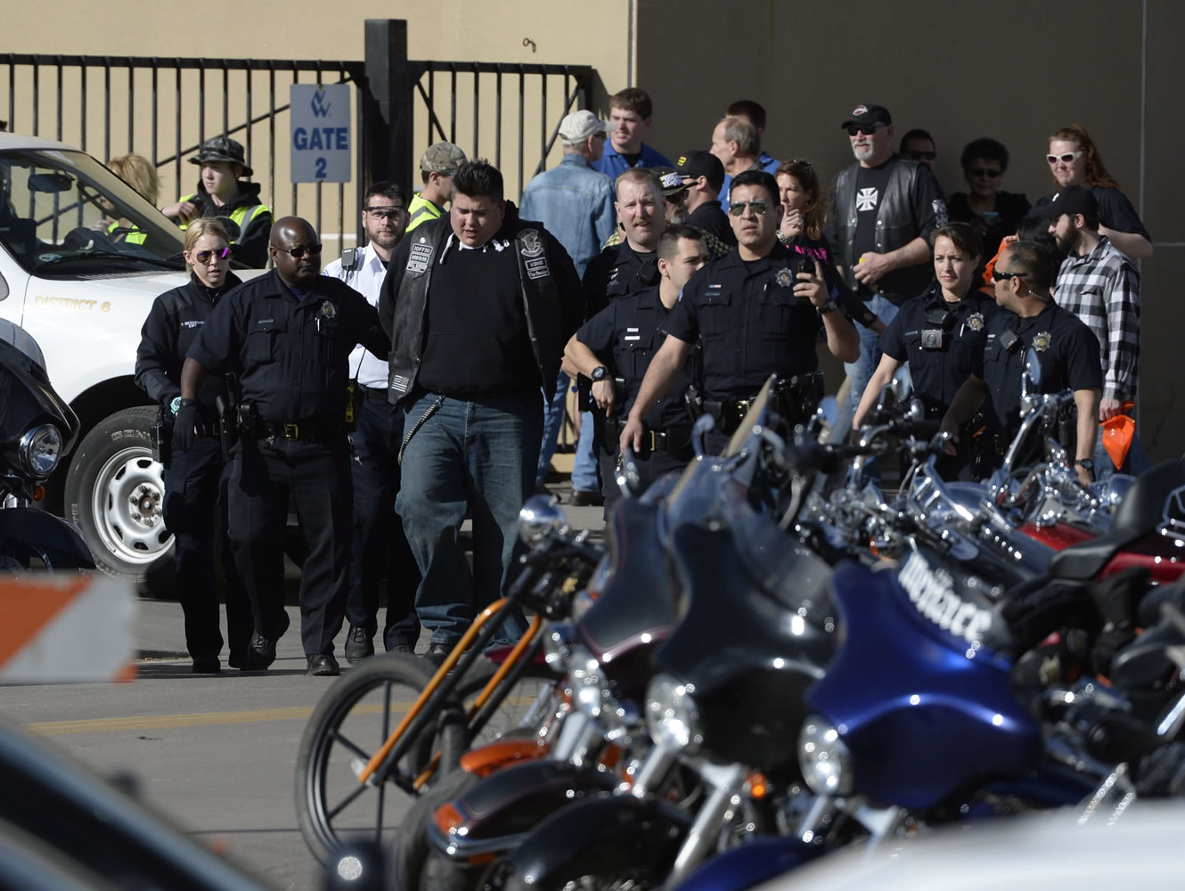 Denver Police escort a man away from the National Western Complex on Saturday in Denver. Denver police say multiple people were injured in a deadly stabbing and shooting at The Colorado Motorcycle Expo.