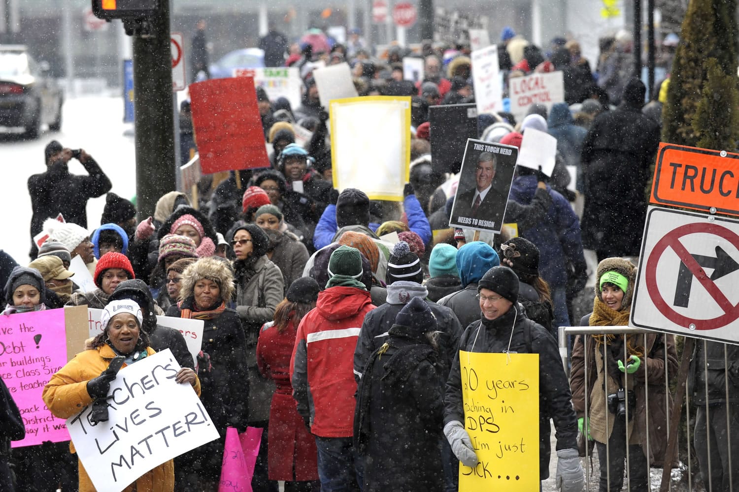 Teacher Denice McGee, bottom left, holds a sign as she and other protesters wait to cross the street Wednesday in Detroit. Most of Detroit&#039;s public schools closed for the day due to teacher absences, as disgruntled educators stepped up protest efforts.