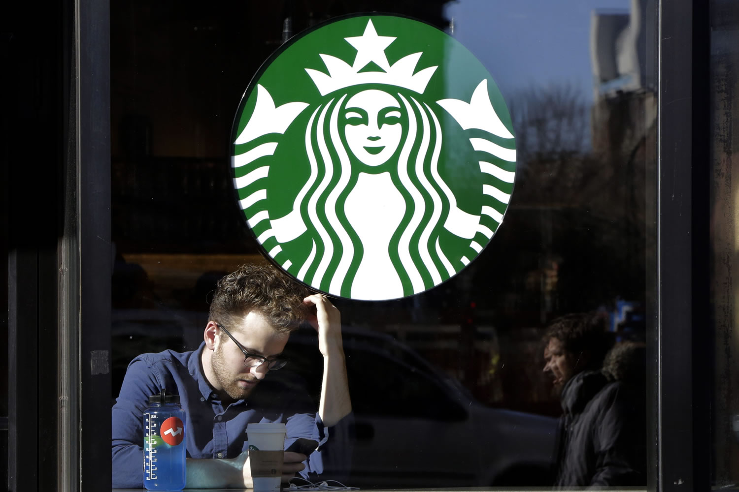 A man sits in a Starbucks in New York.  Starbucks missed revenue but  topped sales.