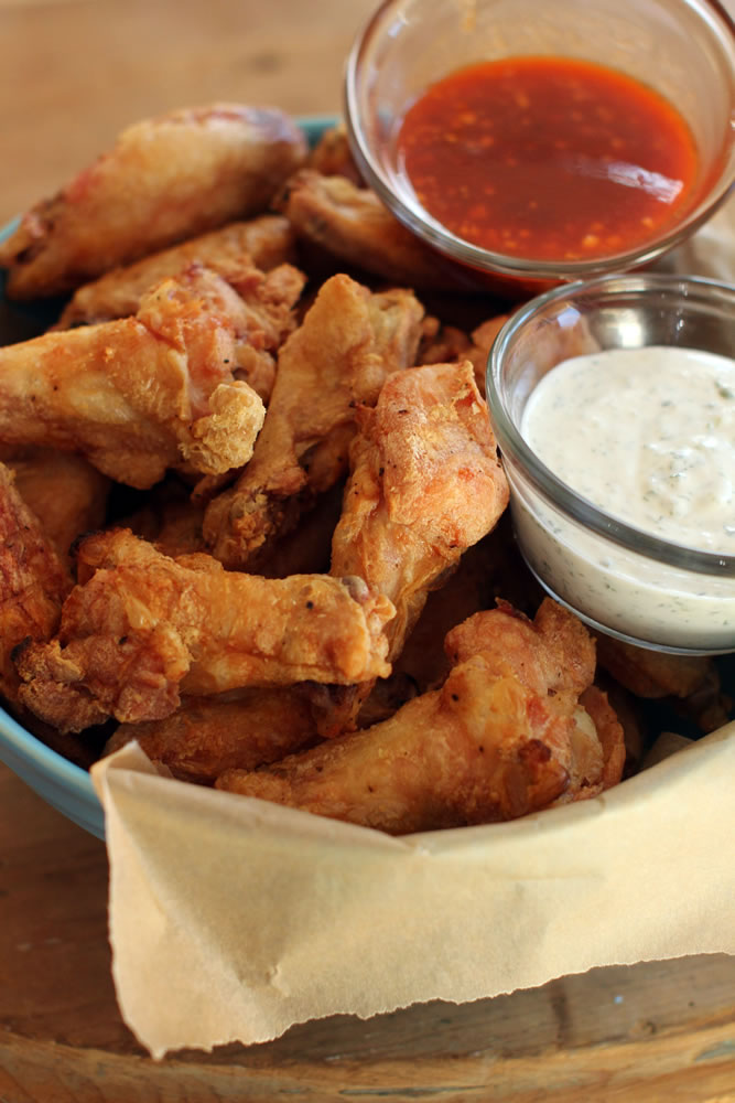 Hands-off party wings with cilantro-sour cream dip and honey-Sriracha sauce require very little effort, which is perfect if you want to relax on Super Bowl Sunday.