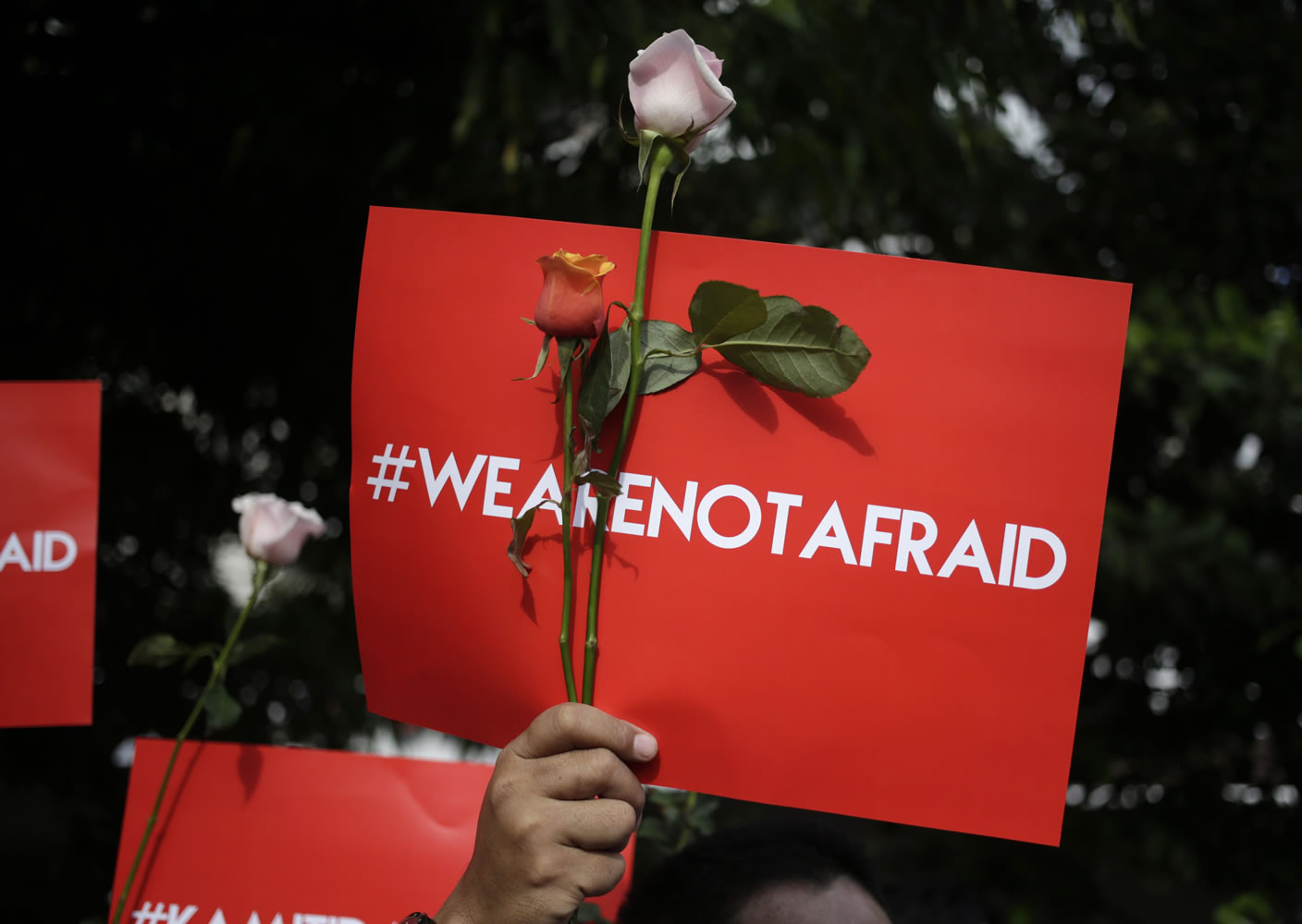 An activist holds a poster Friday during a rally condemning Thursday&#039;s attack, outside the Starbucks cafe where it took place in Jakarta, Indonesia. Indonesians were shaken but refusing to be cowed a day after a deadly attack in a busy district of central Jakarta that has been claimed by the Islamic State group.