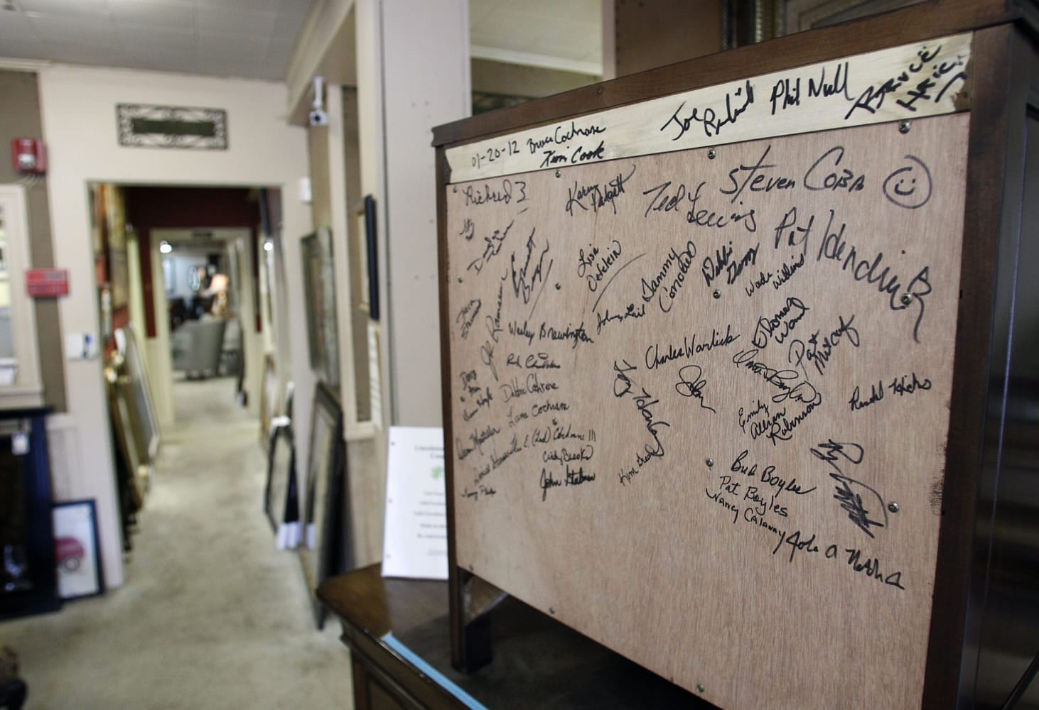 This Friday, March 16, 2012 photo shows the first piece that came from the Lincolnton Furniture Company, a wooden nightstand, signed by all the employees working at the time of the startup, on display at the Carolina Furniture Mart in Lincolnton, N.C. Five generations of Cochranes had been furniture makers, but by the mid-1990s the trade was moving to China, land of cheap labor.