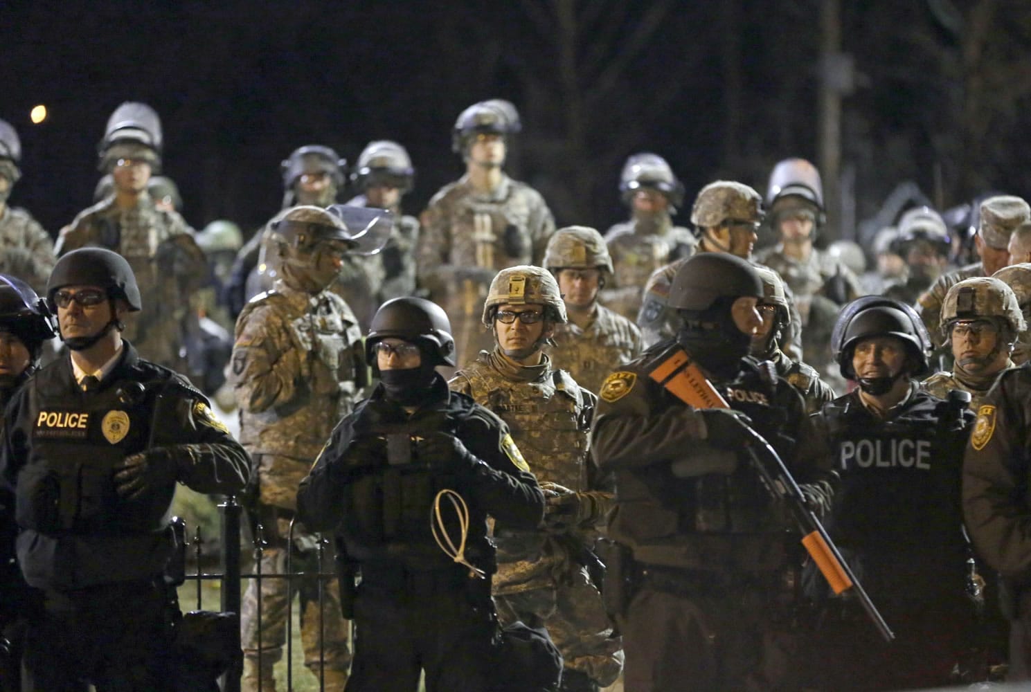 FILE - In this Friday, Nov. 28, 2014, file photo, police and Missouri National Guardsmen face protesters gathered in front of the Ferguson Police Department in Ferguson, Mo. The Justice Department has reached a tentative agreement with Ferguson on systemic changes following the fatal police shooting of 18-year-old Michael Brown in 2014, city officials announced Wednesday, Jan. 27, 2016. The recommended overhaul to the Ferguson Police Department and the city?s municipal court system follows seven months of negotiations and likely averts a civil rights lawsuit that federal officials can bring against departments that resist changing their policing practices.