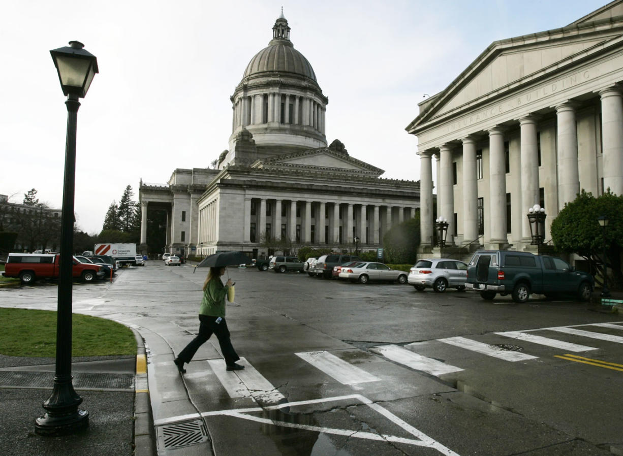 A pedestrian uses an umbrella as she crosses the street at the Capitol in Olympia.