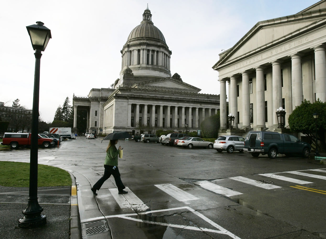 A pedestrian uses an umbrella as she crosses the street at the Capitol in Olympia.
