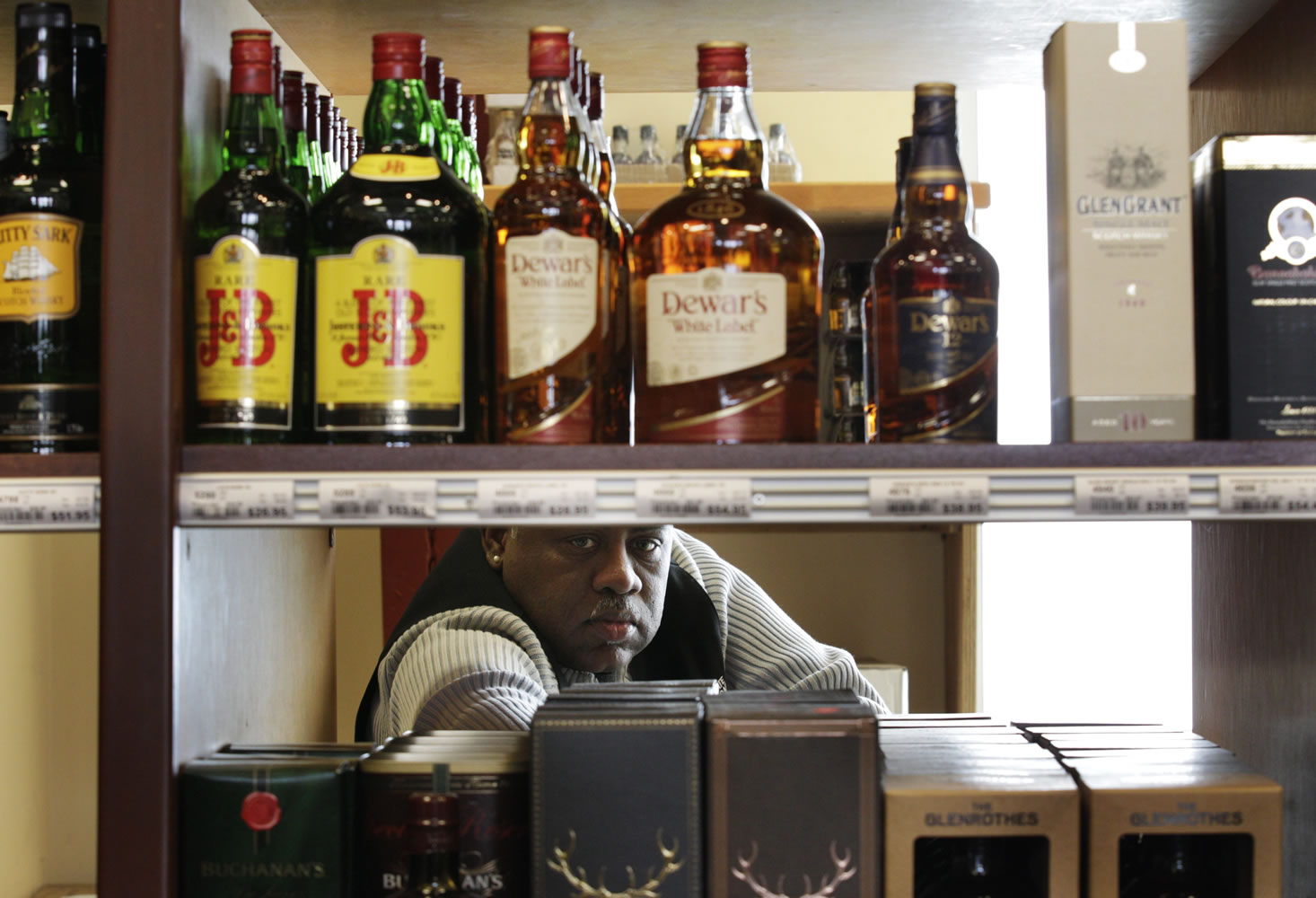 Thomas Burns stocks shelves as he works at a state-run liquor store Wednesday in Seattle.