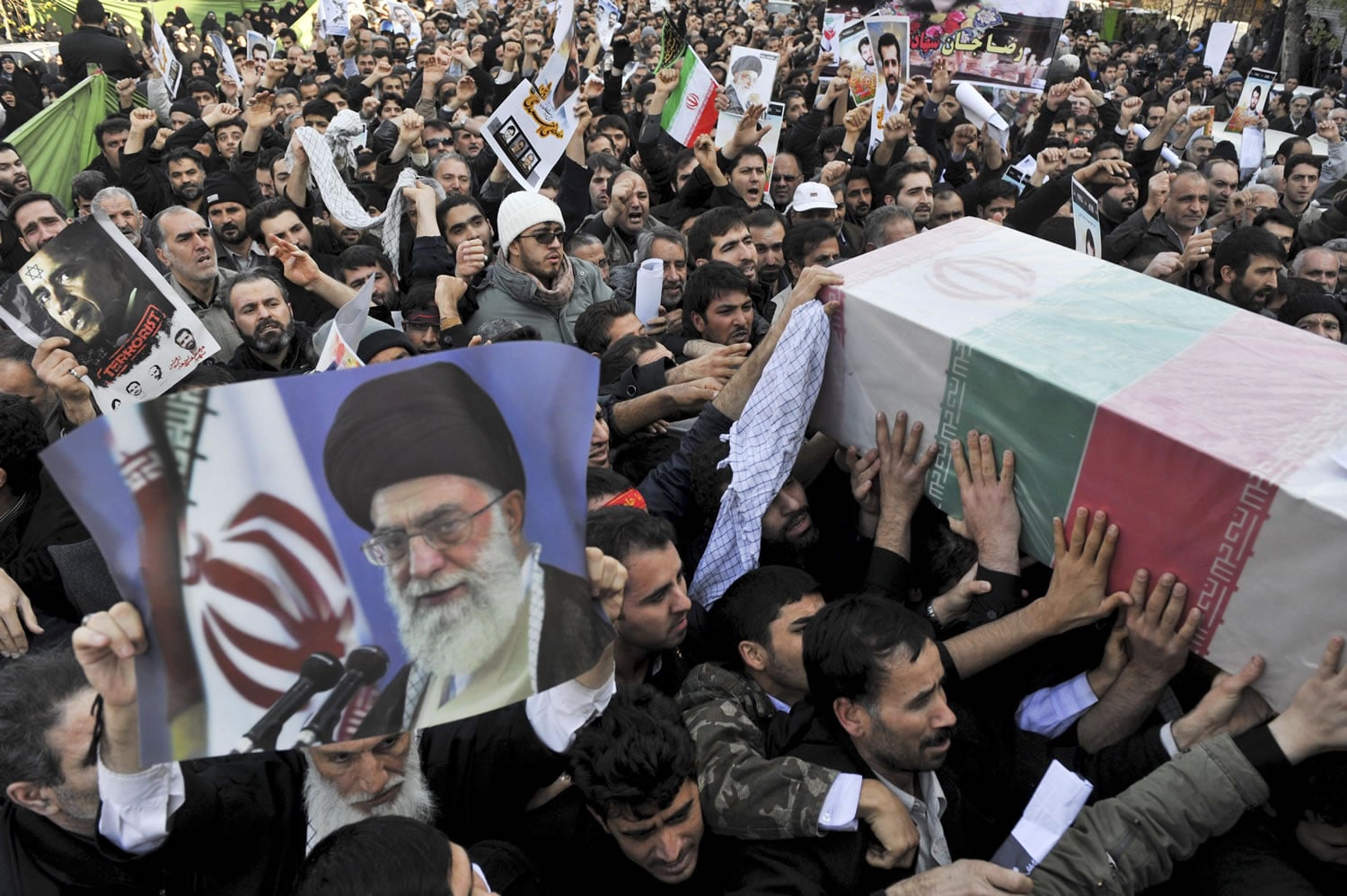 Beside a poster of Iranian supreme leader Ayatollah Ali Khamenei, mourners Friday carry a flag draped coffin of Mostafa Ahmadi Roshan, director of the Natanz uranium enrichment facility who was killed in a brazen daylight assassination when two assailants on a motorcycle attached a magnetic bomb to his car Wednesday.