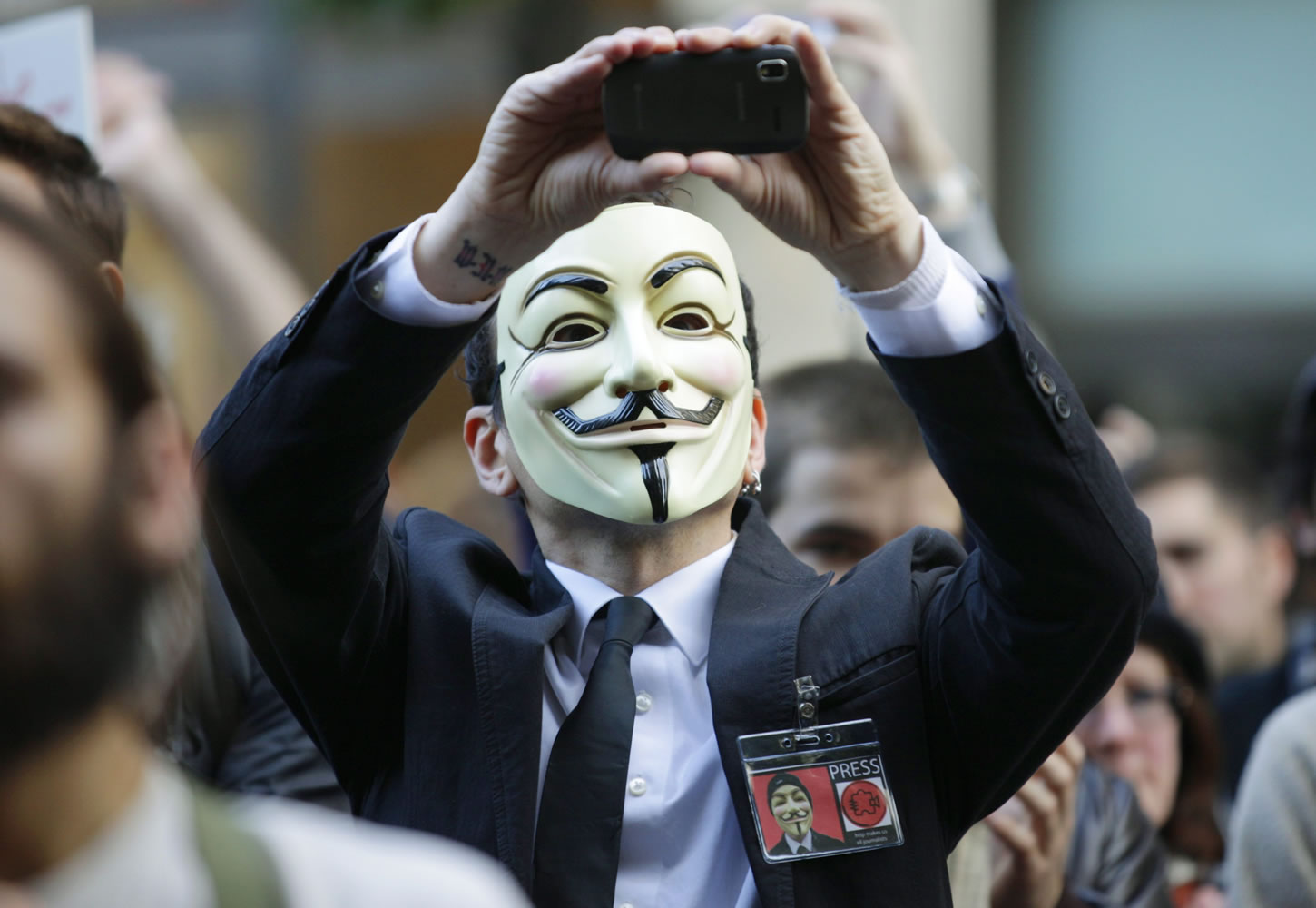 A protester with the &quot;Occupy Seattle&quot; movement wears a Guy Fawkes mask and takes a photo with a mobile phone as he demonstrates, in downtown Seattle. From New York to San Francisco to London, some of the demonstrators decrying a variety of society's ills are sporting stylized masks loosely modeled on a 17th-century English terrorist, whether they know it or not.