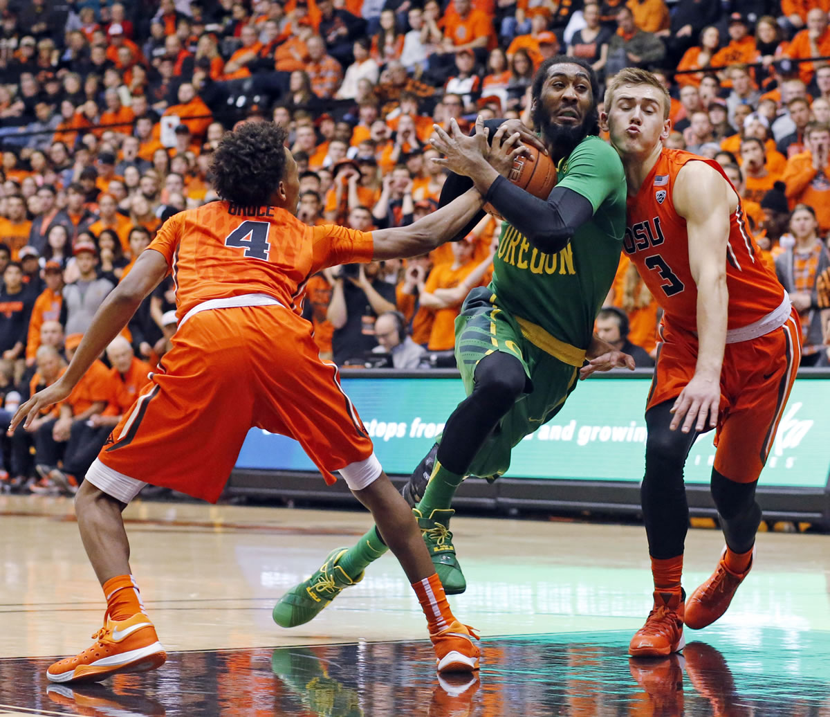 Oregon's Dwanye Benjamin, center, drives between Oregon State's Derrick Bruce, left, and Tres Tinkle, right, in the first half of an NCAA college basketball game in Corvallis, Ore., Sunday, Jan. 3, 2016. (AP Photo/Timothy J.