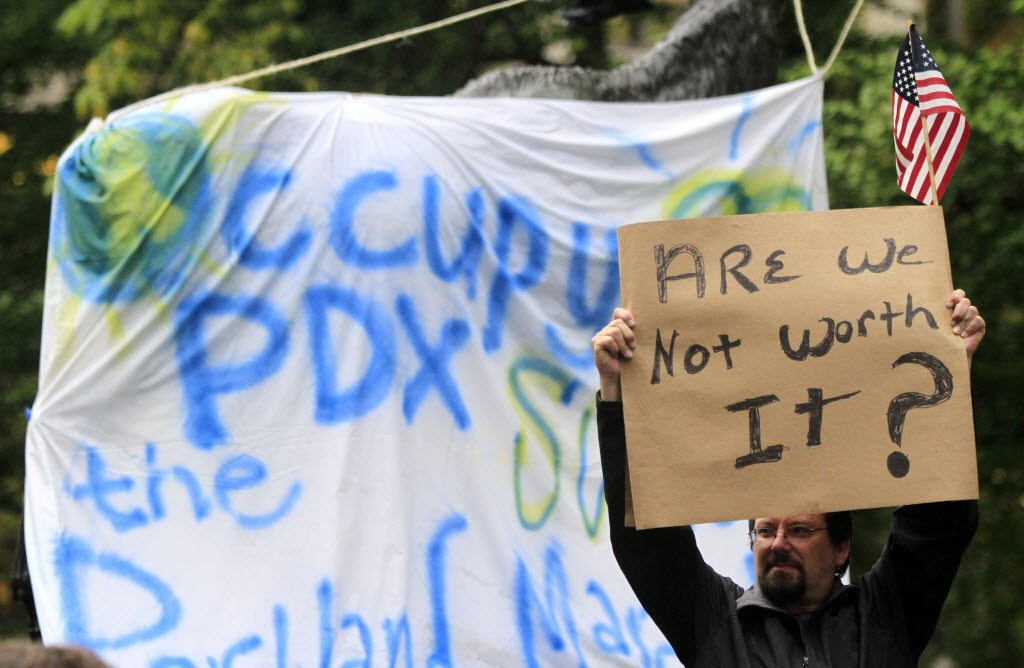 Steve Martinez holds a sign and American flag at the Occupy Portland camp, Friday.