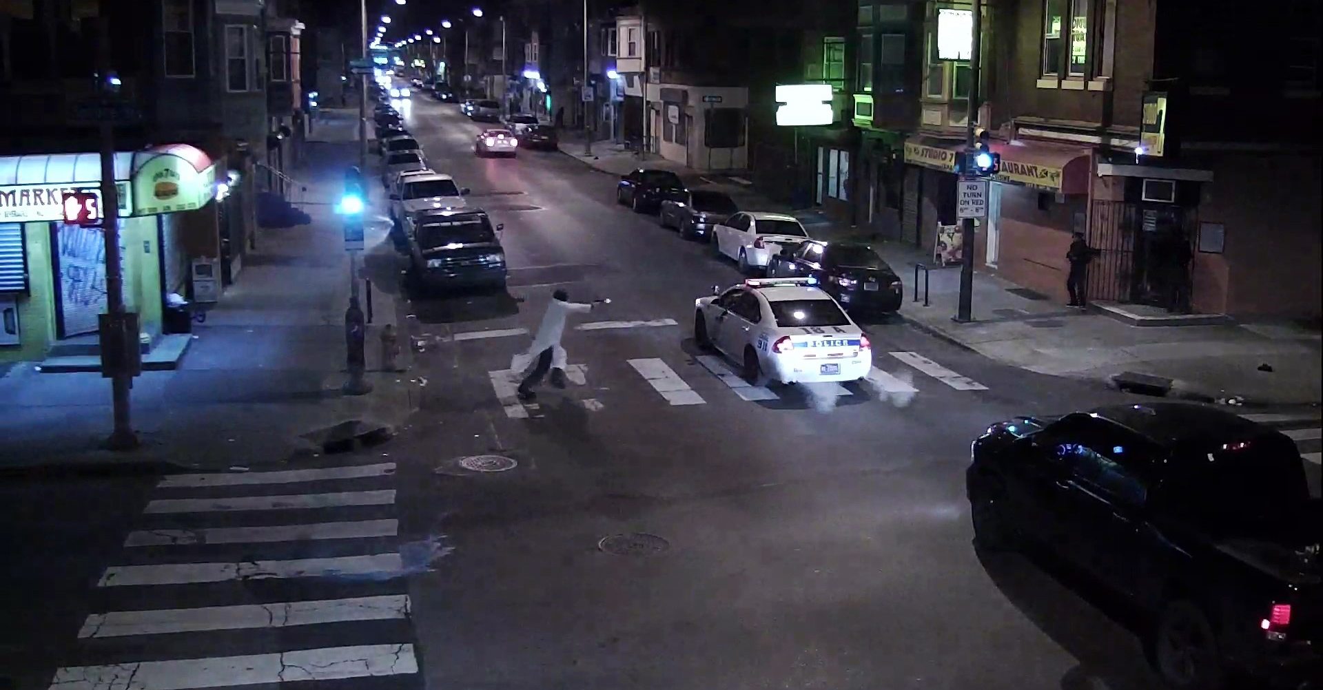 In this image from video, a man identified as Edward Archer runs with a gun toward a police car driven by Officer Jesse Hartnett on Thursday in Philadelphia.