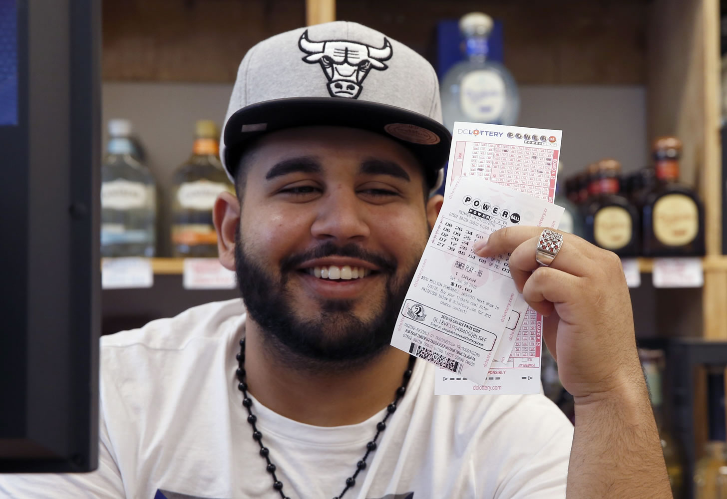 Samir Akhter, the owner of Penn Branch Liquor, smiles as he holds up Powerball tickets that he just sold, Saturday, Jan. 9, 2016 in Washington. Officials say it's increasingly likely that someone will win the $900 million Powerball jackpot, which grew by $100 million just hours before Saturday night's drawing.