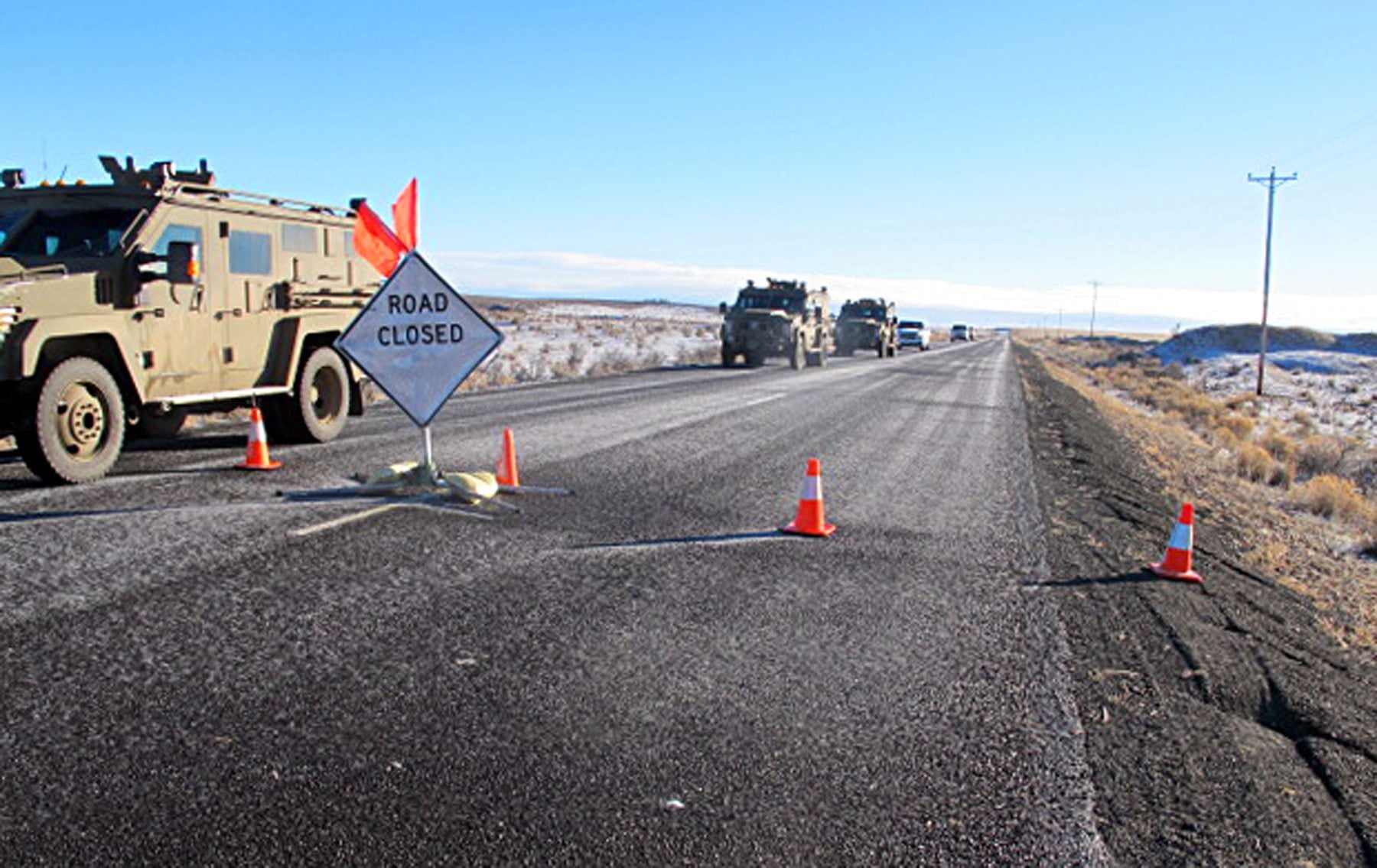 A convoy of armored vehicles and SUVs rolls past a barricade on the road near the Malheur National Wildlife Refuge near Burns, Ore., Saturday, Jan. 30, 2016. The remnants of an armed group occupying the refuge to protest federal land policies say they won't leave until they get assurances they won't be arrested.(AP Photo/Nicholas K.