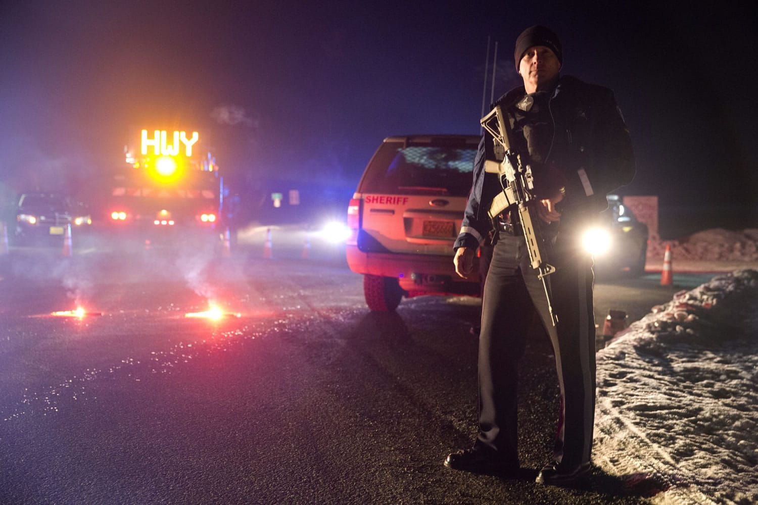 Sgt. Tom Hutchison stands in front of an Oregon State Police roadblock on Highway 395 between John Day and Burns by Oregon State police officers Tuesday, Jan. 26, 2016. Authorities say shots were fired Tuesday during the arrest of members of an armed group that has occupied a national wildlife refuge in Oregon for more than three weeks. The FBI said authorities arrested Ammon Bundy, 40, his brother Ryan Bundy, 43, Brian Cavalier, 44, Shawna Cox, 59, and Ryan Payne, 32, during a traffic stop on U.S. Highway 395 Tuesday afternoon. Authorities said another person, Joseph Donald O'Shaughnessy, 45, was arrested in Burns.