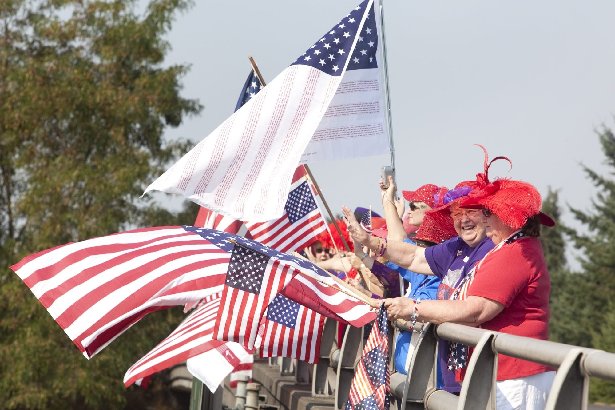 Members of Washington and Oregon chapters of the Red Hat Society waved flags on the Northeast Ninth Street overpass at Interstate 205, near Northeast 112th Avenue on Sunday, Sept.