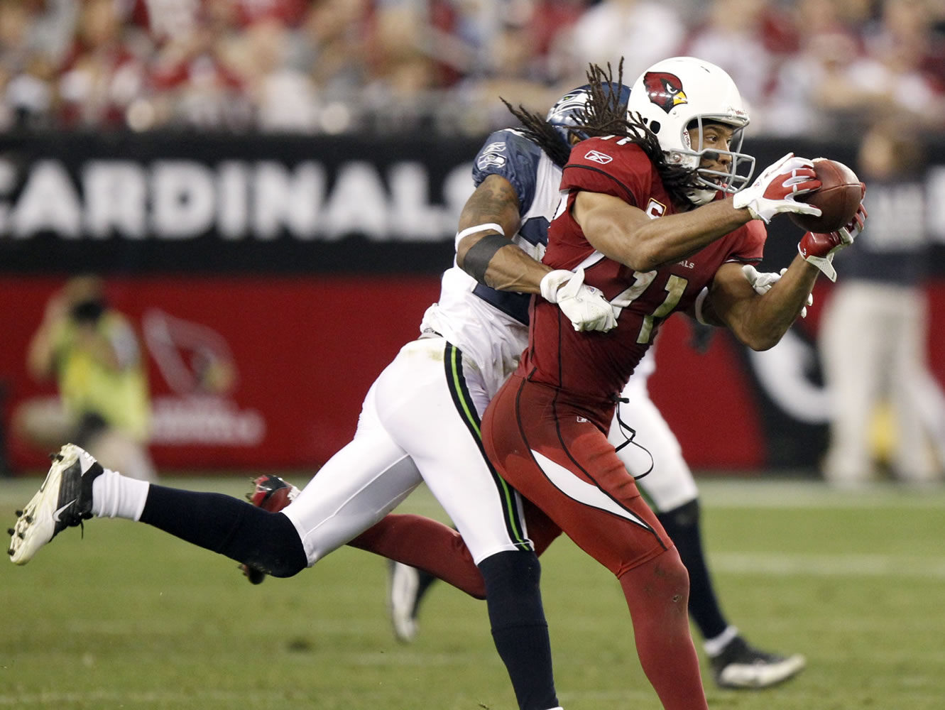Arizona Cardinals wide receiver Larry Fitzgerald, right, makes a reception as he is covered by Seattle Seahawks cornerback Richard Sherman, left, during the fourth quarter Sunday.