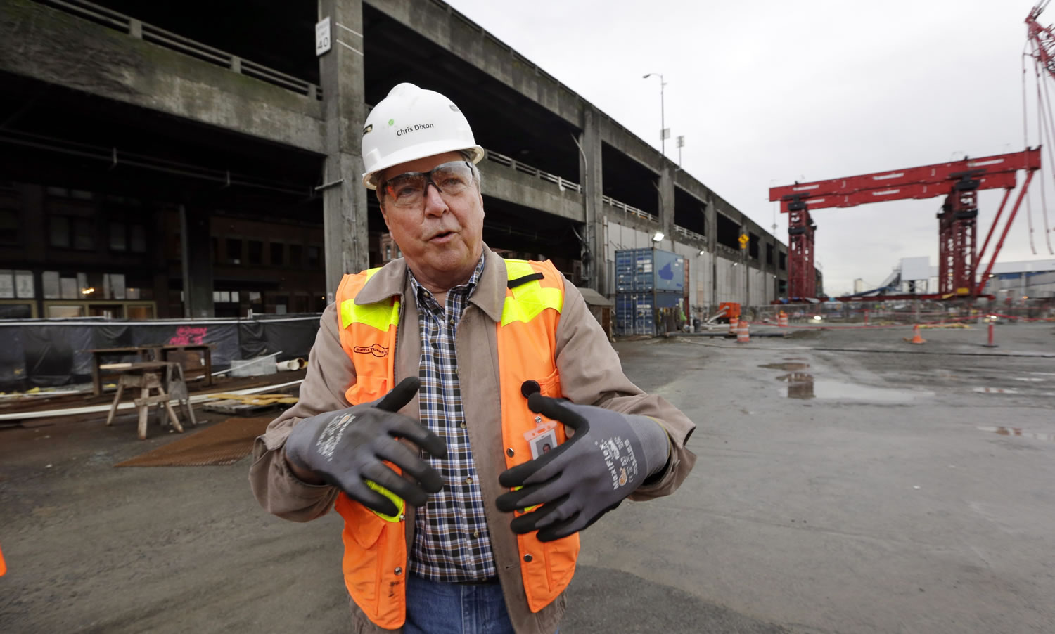 Seattle Tunnel Partners Project Manager Chris Dixon speaks with media members Wednesday in Seattle at the site of a giant tunnel being dug below him to replace the elevated Alaskan Way Viaduct roadway behind him.