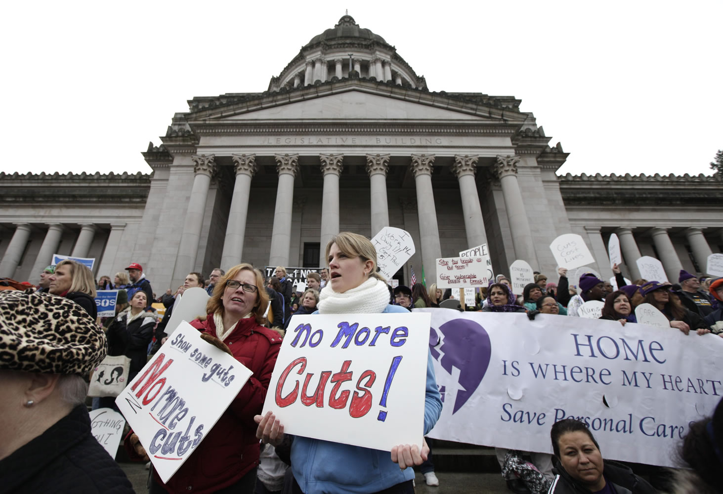 Protesters, including Regan Bailey, center left, and Heather McKimmie, center right, both of Seattle, demonstrate against budget cuts outside the Capitol in Olympia on Monday, the first day of a special session of the Washington State Legislature.