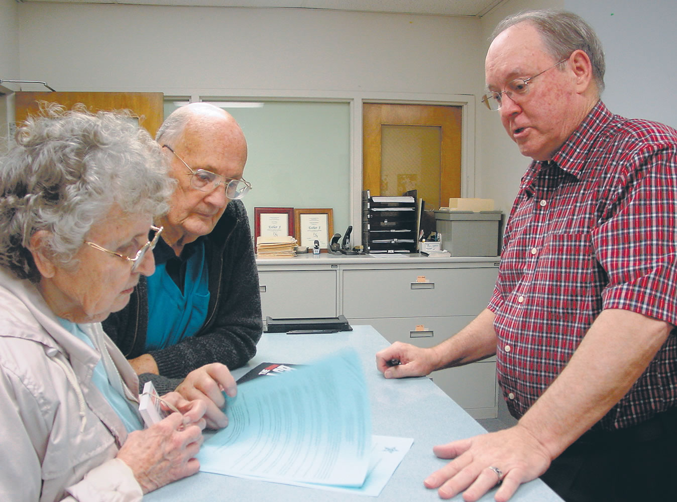 Marty and Harry Smedes, left, go over Mrs. Smedes' application for a concealed weapon permit  Thursday, May 24, 2012 with Steve Vorberg at the Josephine County Sheriffis Office in Grants Pass, Ore. As the sheriff's goes through with cutting his office to the bone, applications for concealed weapons permits have tripled in the month of May over the same month last year.