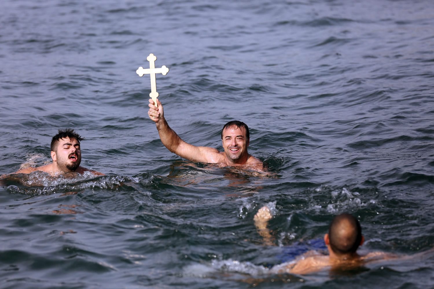 Lefteris Chrisomallos from Greece holds up a wooden cross after he retrieved it during an Epiphany ceremony Wednesday in Izmir, Turkey.