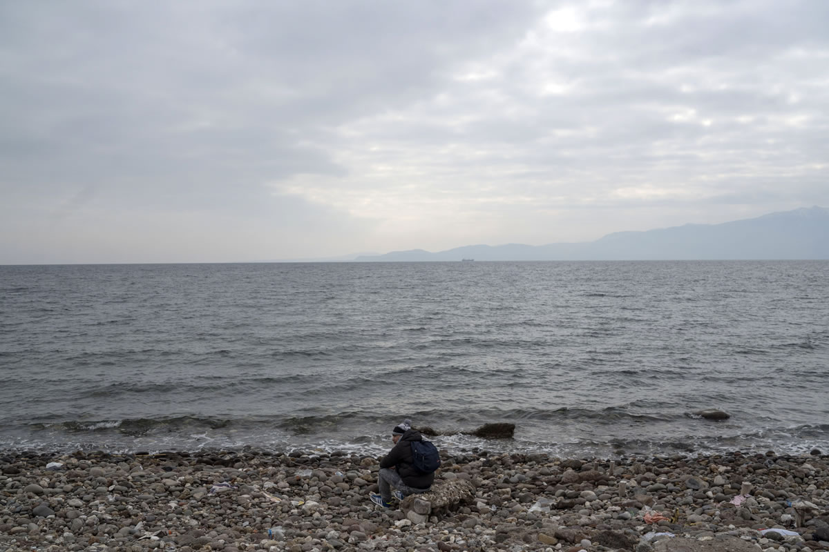 In this Friday, Jan. 29, 2016 photo made available Saturday, a migrant waits before travelling to Greek island of Lesbos, near Ayvacik, Turkey. A boat smuggling migrants to Greece slammed into rocks off the Turkish coast near Ayvacik on Saturday and capsized, killing at least 37 people including five children, as the choppy Aegean Sea continued to claim asylum-seekers' lives this month at an appalling pace, officials said.