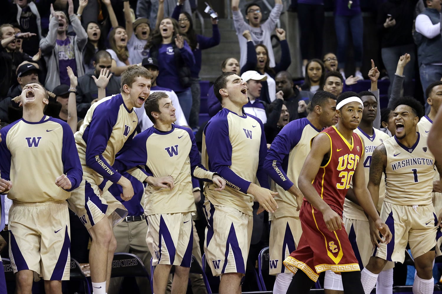 Players on the Washington bench erupt in cheers as Southern California's Elijah Stewart walks past on a scoring run by Washington late the second half of an NCAA college basketball game Sunday, Jan. 3, 2016, in Seattle. Washington won 87-85.