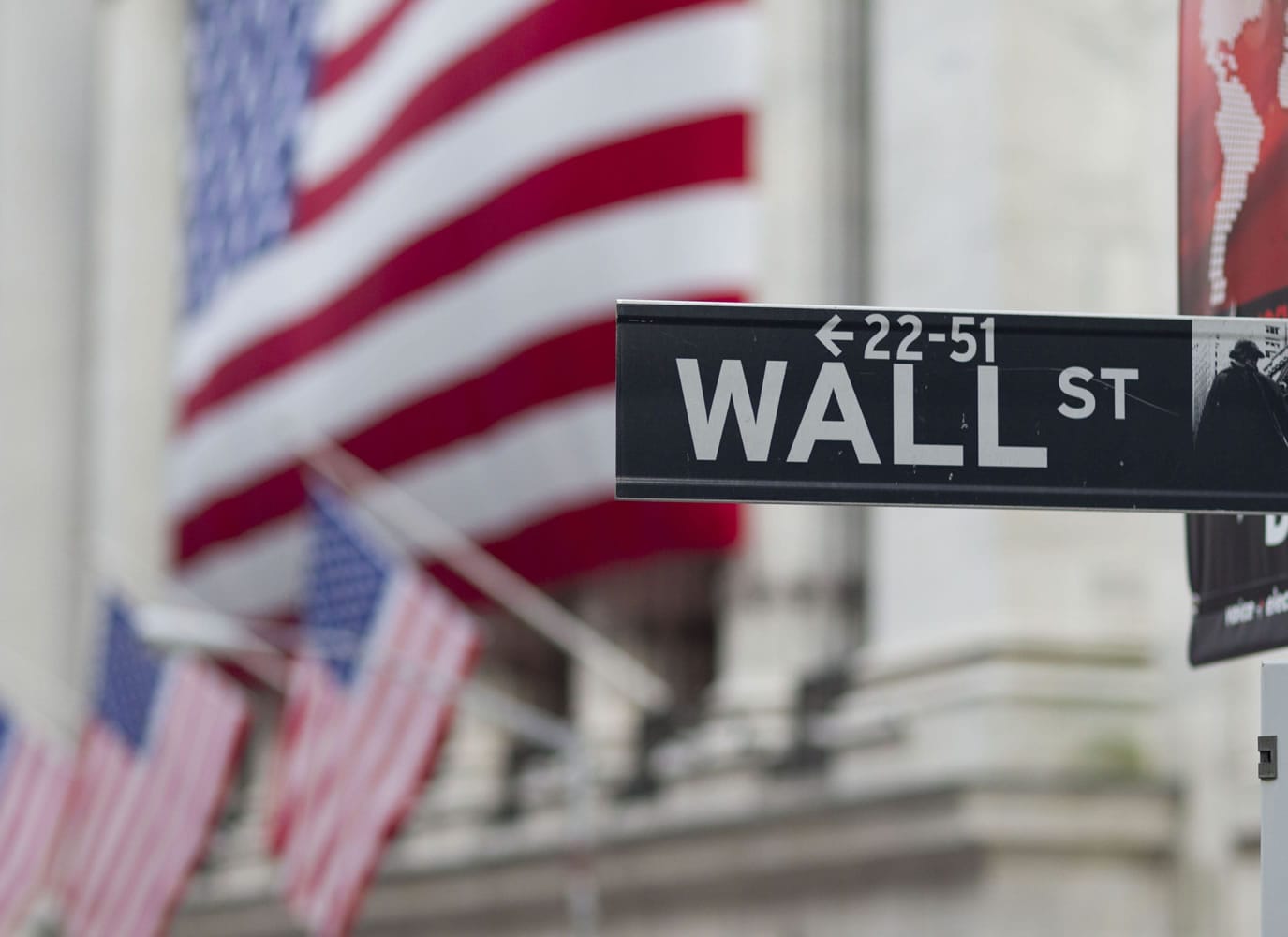 A Wall Street sign mixes with flags hanging near the New York Stock Exchange this week.