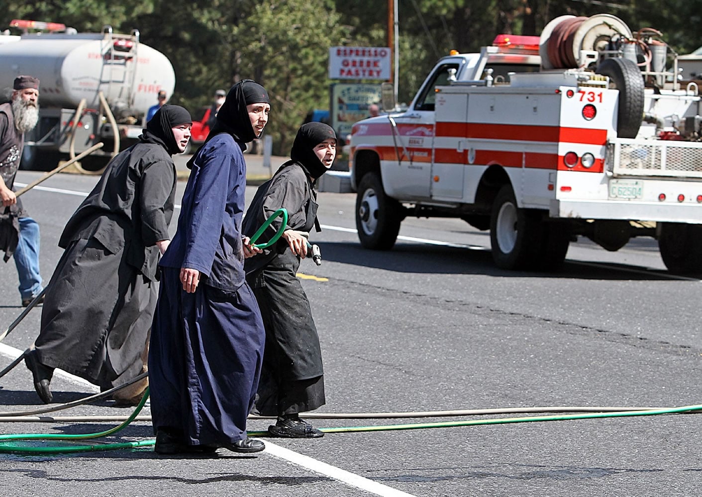 Three sisters from Saint Johns Monastery, about 10 miles east of Goldendale, race across Highway 97 on Wednesday.  The nuns were running garden hoses across the highway to fight the fire, along with using rags to beat the flames down near their monastery.