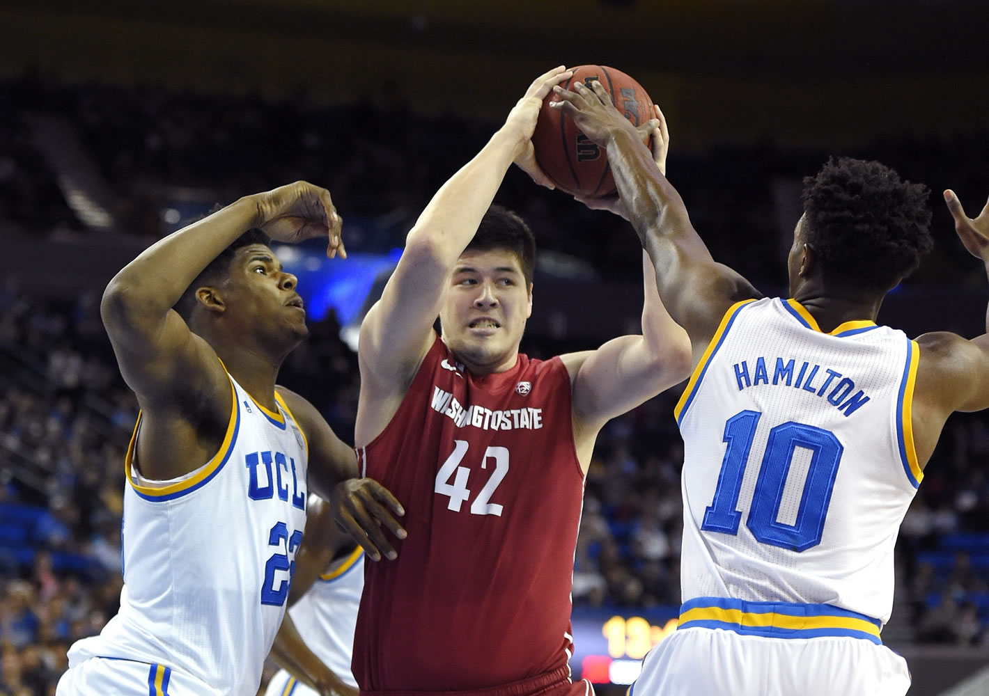 Washington State center Conor Clifford, center, tries to pass under pressure from UCLA forward Tony Parker, left, and guard Isaac Hamilton during the first half of an NCAA college basketball game Saturday, Jan. 30, 2016, in Los Angeles. (AP Photo/Mark J.