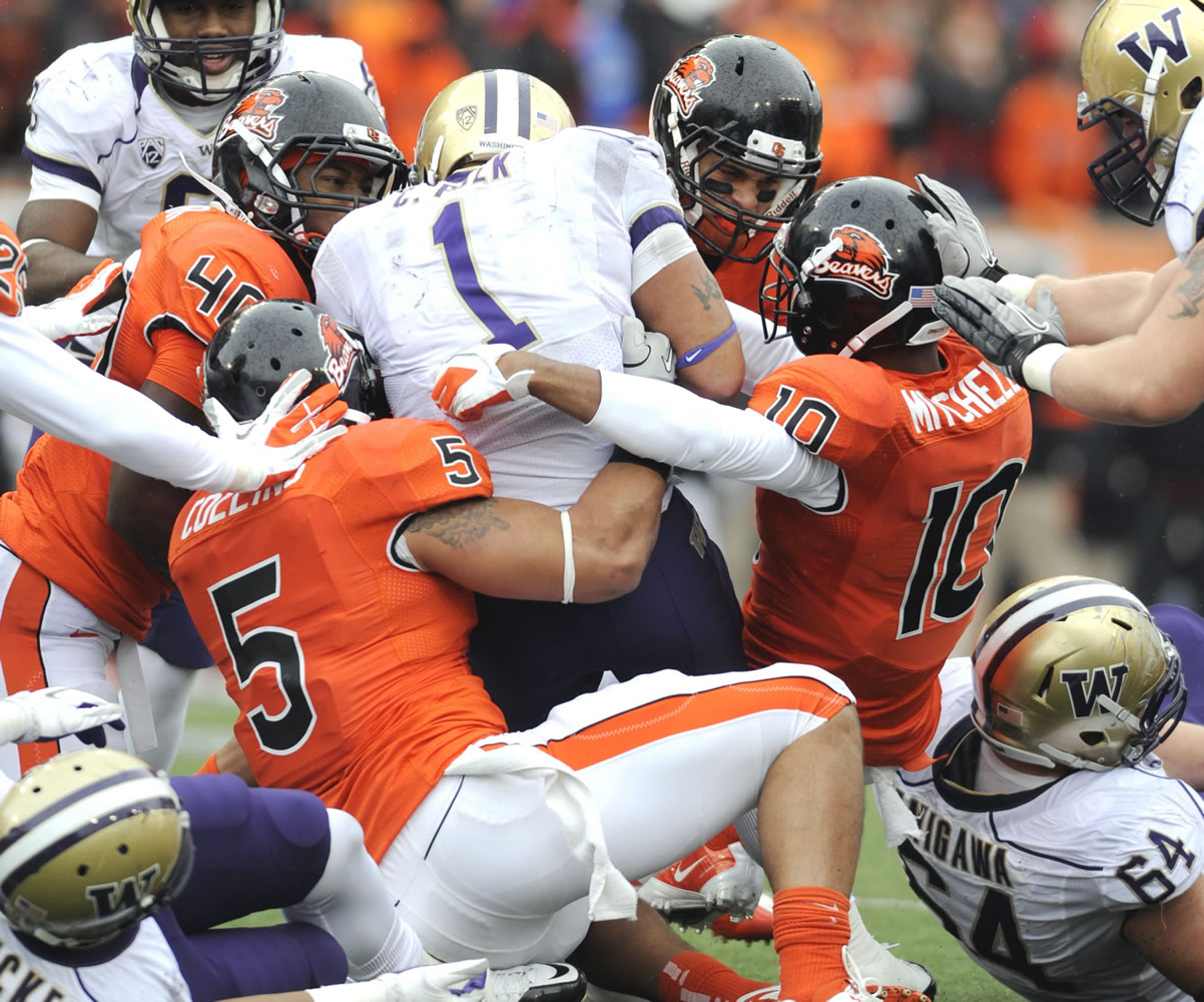 Oregon State's players, including Cameron Collins (5), Lance Mitchell (10) and Michael Doctor (40), tackle Washington's Chris Polk (1) during the first half Saturday.