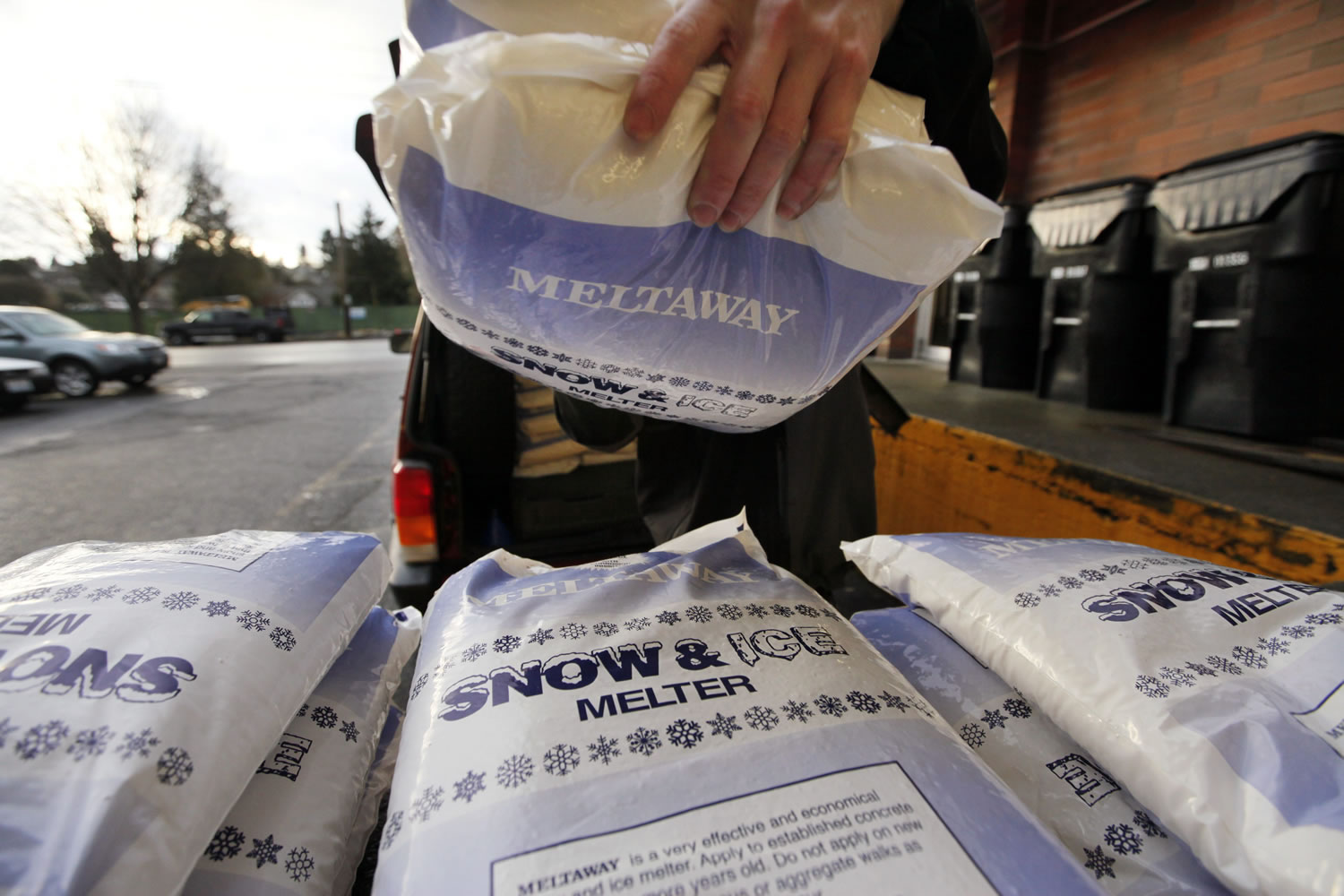 Clerk Joel Bartlett stacks bags of a de-icing product Tuesday at a Seattle hardware store, after making a run to the warehouse when supplies ran out.