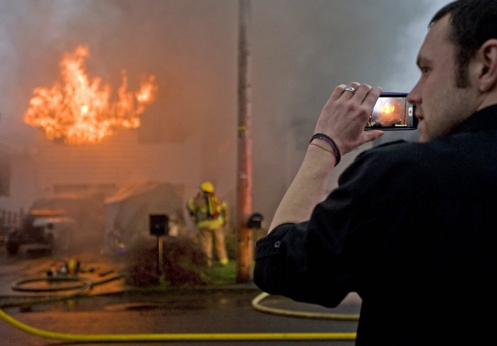 Douglas Pratt records video on his phone of a two-alarm fire at his neighbor's Hazel Dell home on Monday.