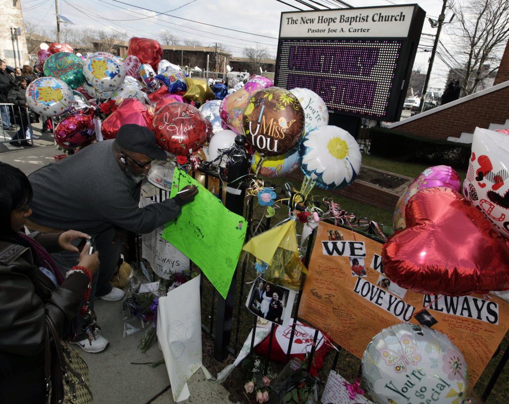 People sign cards and take photographs at a memorial to Whitney Houston outside New Hope Baptist Church in Newark, N.J., Friday.