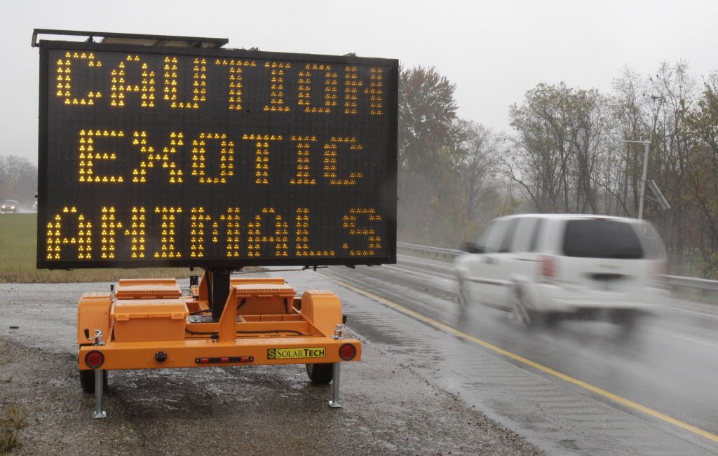 A sign warning motorists that exotic animals are on the loose rests on I-70 Wednesday near Zanesville, Ohio.
