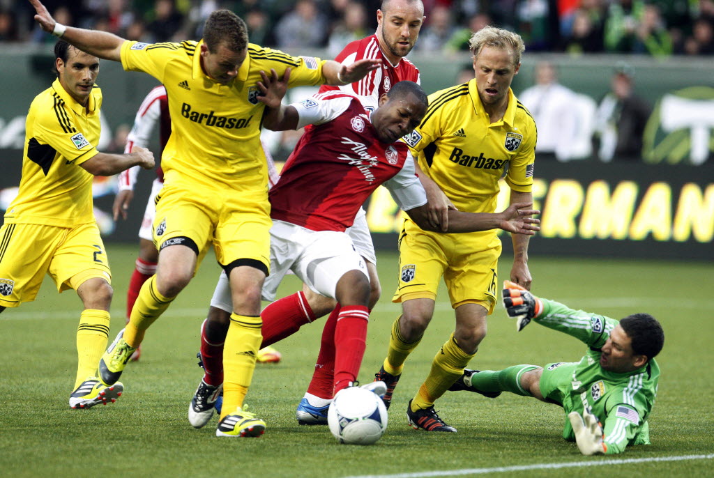 Columbus Crew goalie Andy Gruenebaum makes a save as Portland Timbers' Darlington Nagbe, center, drives through defenders in the first half during Saturday.
