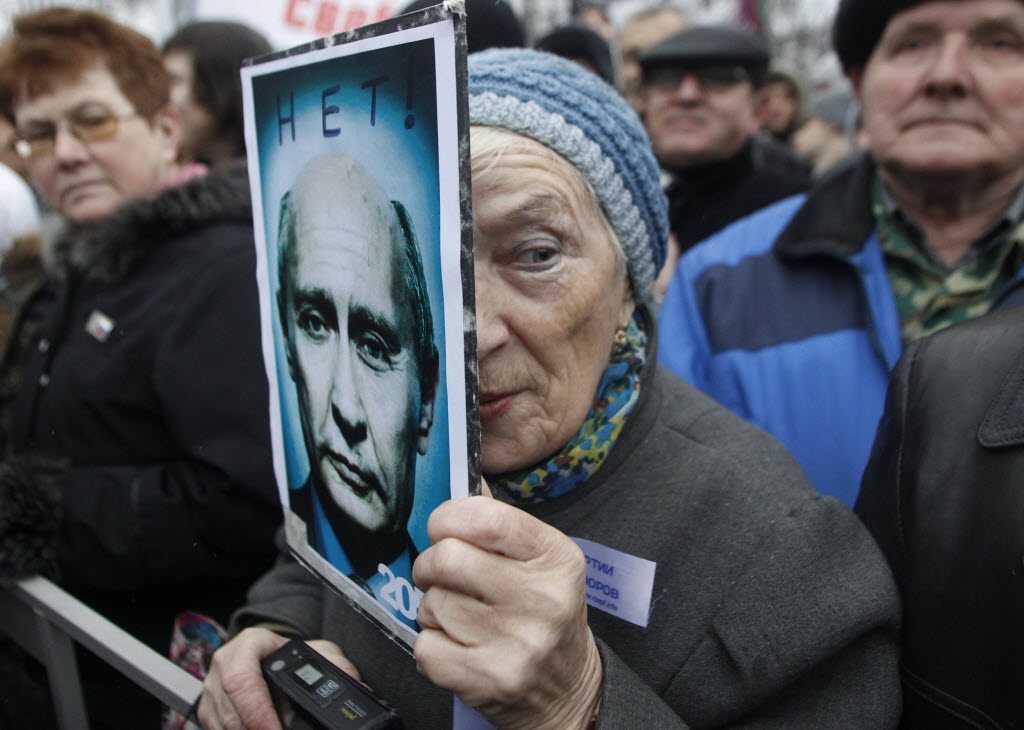 A demonstrator holds a poster showing a manipulated photograph of Russian Prime Minister Vladimir Putin and bearing the words, &quot;No!