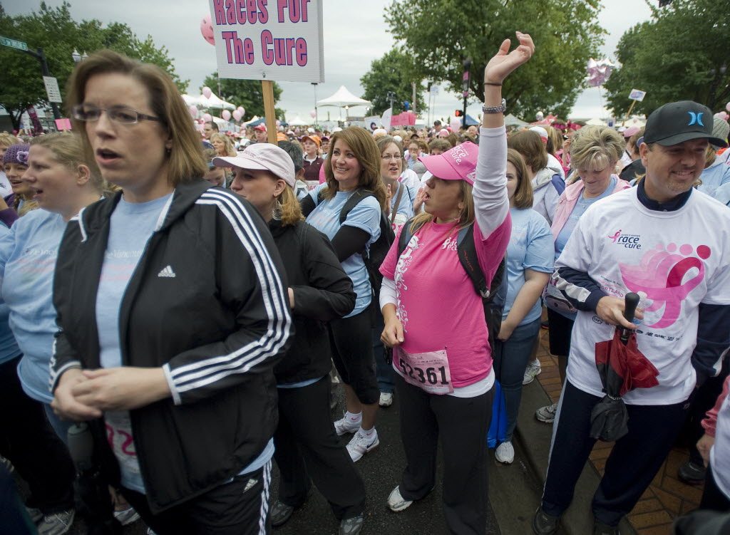 Breast cancer survivor Nell Perdue, center, then 39, of Vancouver reaches skyward as she cheers at the start of the 5K walk during the Race for the Cure in downtown Portland in 2011.