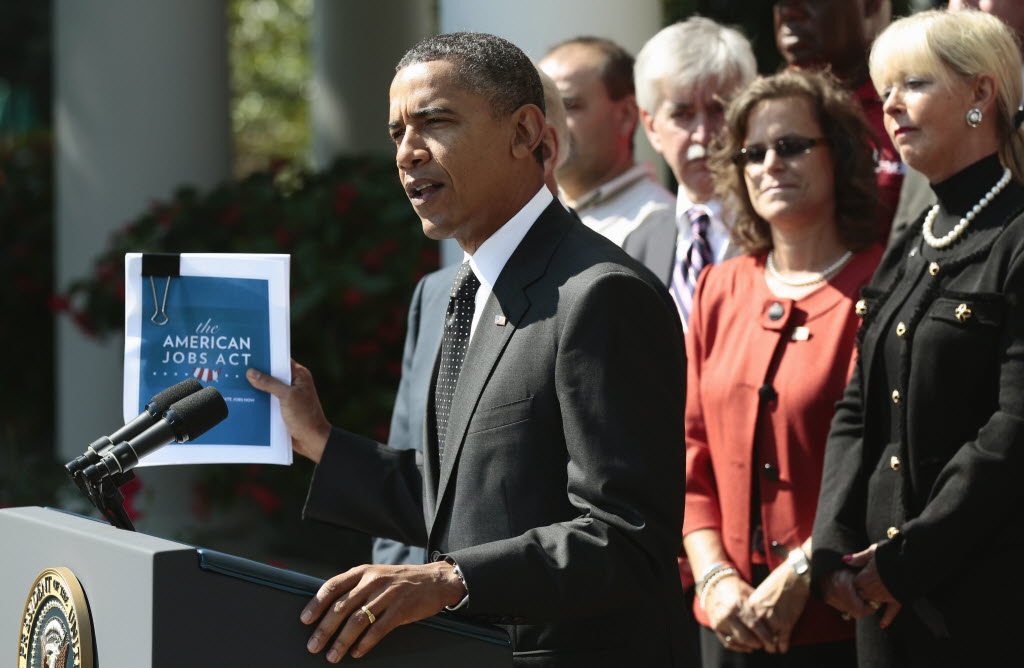 President Barack Obama holds up his proposed American Jobs Act legislation while making a statement in the Rose Garden of the White House in Washington on Monday.